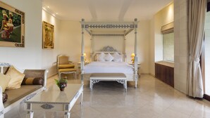 A four-poster bed with a canopy, a sofa with cushions, a small table with a plant, and a window with curtains. - Rijasa Agung Resort Villas (Ubud)