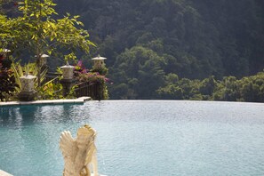 A pool with a statue in the foreground, surrounded by lush greenery and a mountainous backdrop. - Rijasa Agung Resort Villas (Ubud)