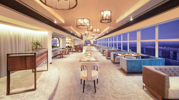 A spacious hotel lobby with a long reception desk, multiple seating areas, and large windows offering city views. - Le Meridien New Delhi (New Delhi)