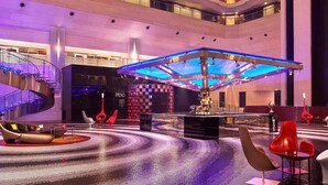 A spacious lobby with a modern design, featuring a central seating area with a unique, illuminated structure, a spiral staircase, and a large digital display. - Le Meridien New Delhi (New Delhi)