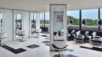 Experience a serene atmosphere in this stylish salon with individual workstations, a high ceiling, and large windows offering views of the surrounding greenery.
