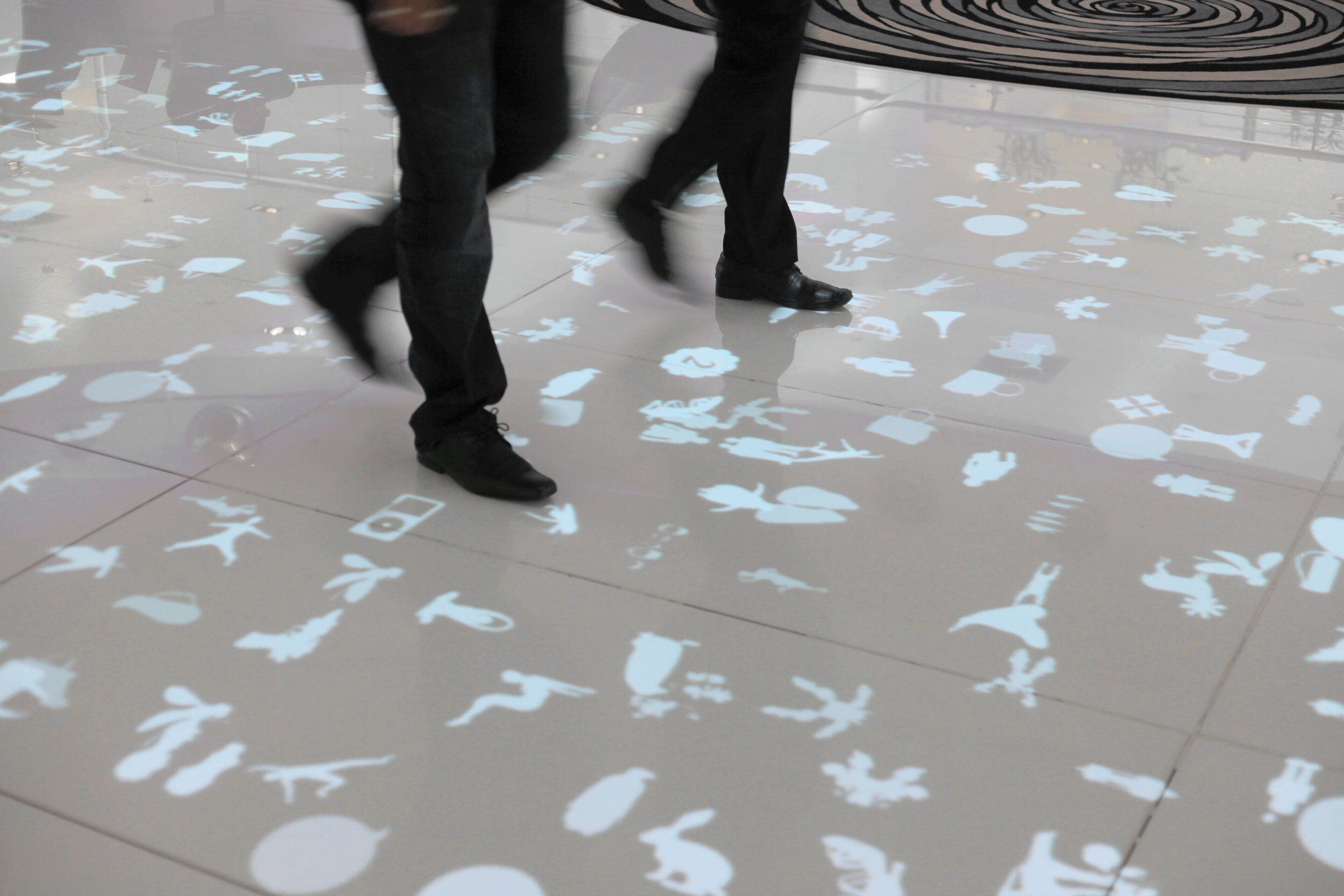 A floor with various white silhouettes of objects and people.