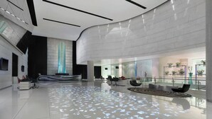 A spacious lobby with a modern design, featuring a reception desk, seating area, and a large glass wall offering views. - Le Meridien New Delhi (New Delhi)