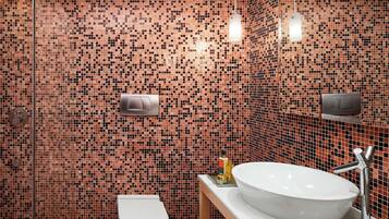A bathroom with a mosaic tile wall, a white sink, and a toilet.