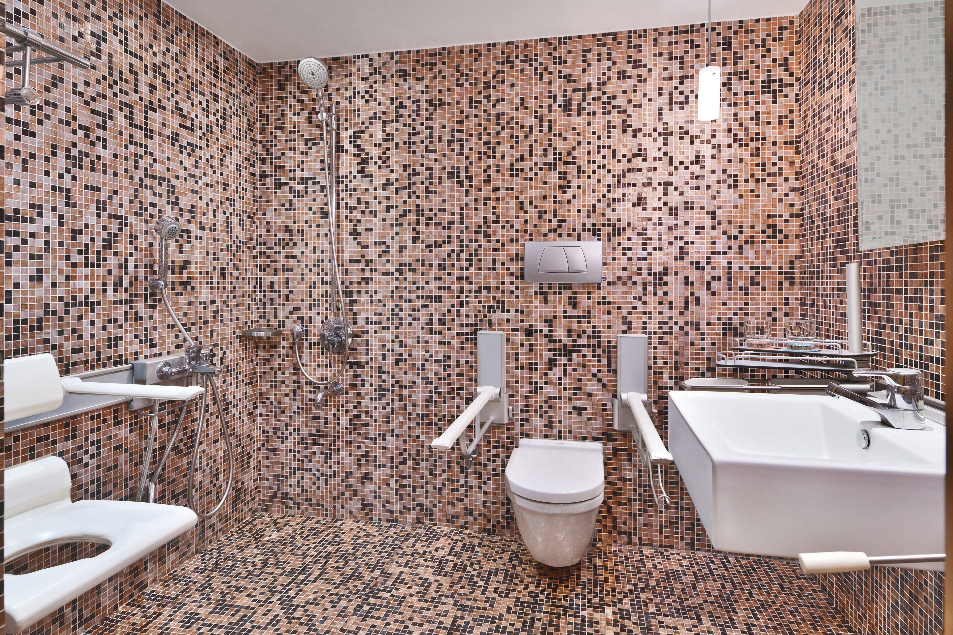A bathroom with a mosaic tile wall, a toilet, a shower, and a bathtub.