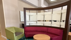 Ein modernes Zimmer mit einem grünen Sessel, einem roten Sofa und einem Holztisch.