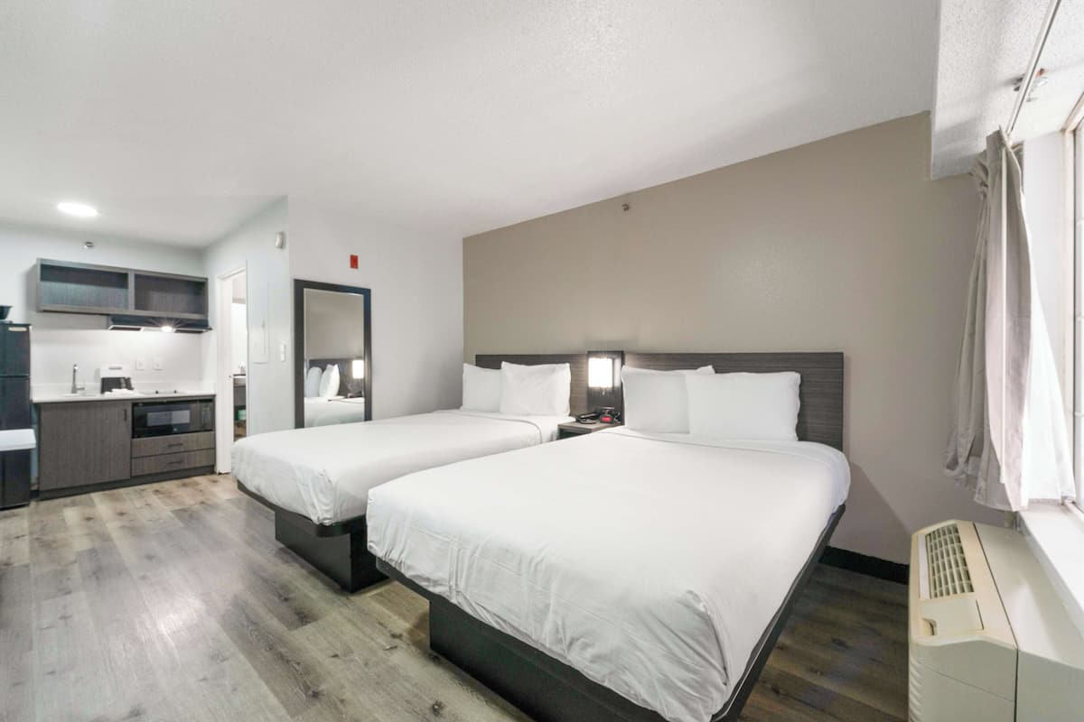 Ein Hotelzimmer mit zwei Betten, einer Küchenzeile und einem Badezimmer.