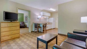 Un ambiente compatto con angolo cottura, televisione, zona pranzo e divano.