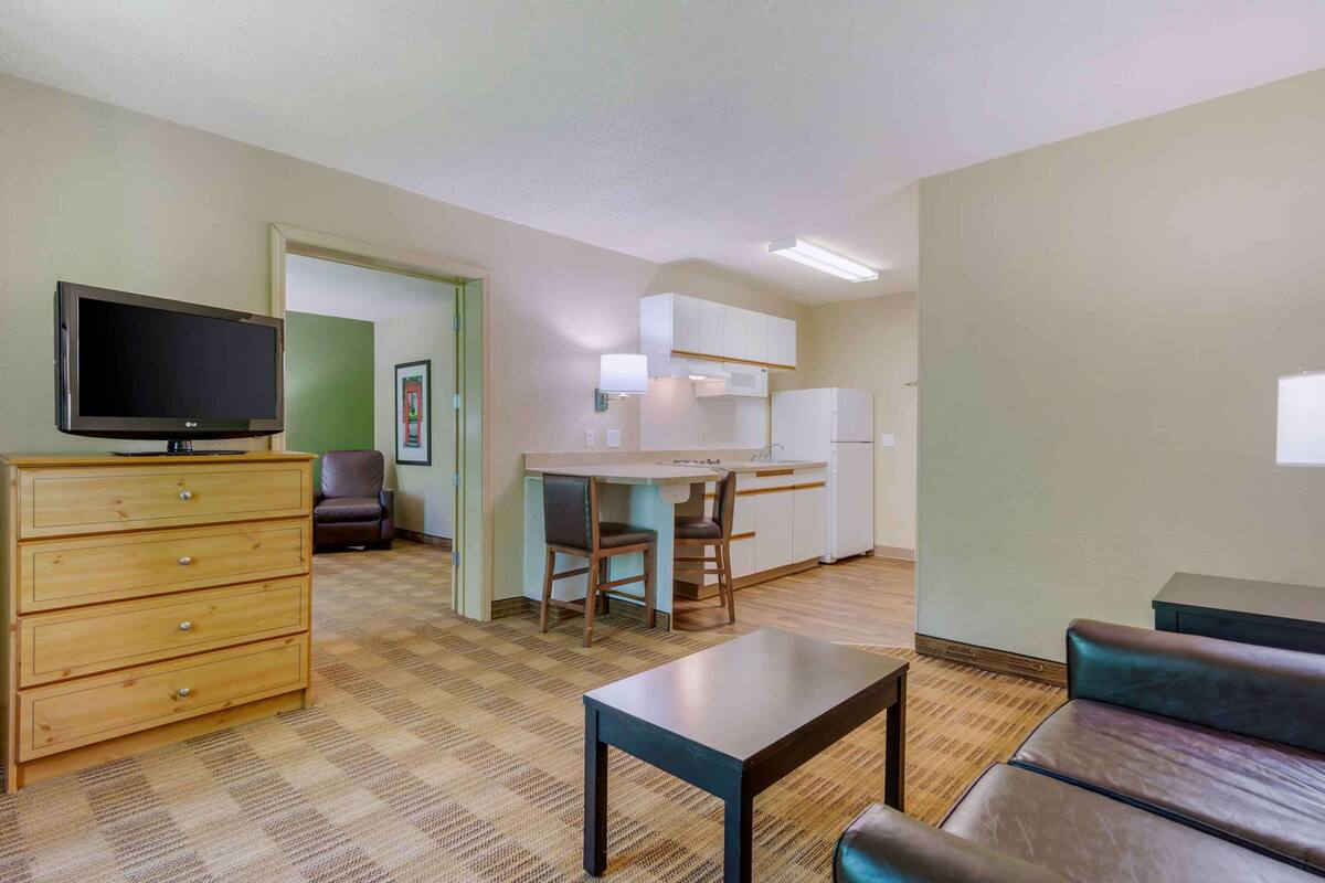 A compact living space with a kitchenette, a television, a dining area, and a sofa.