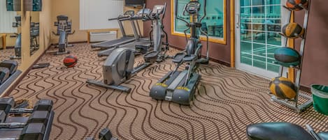 A gym with treadmills, elliptical machines, and free weights.