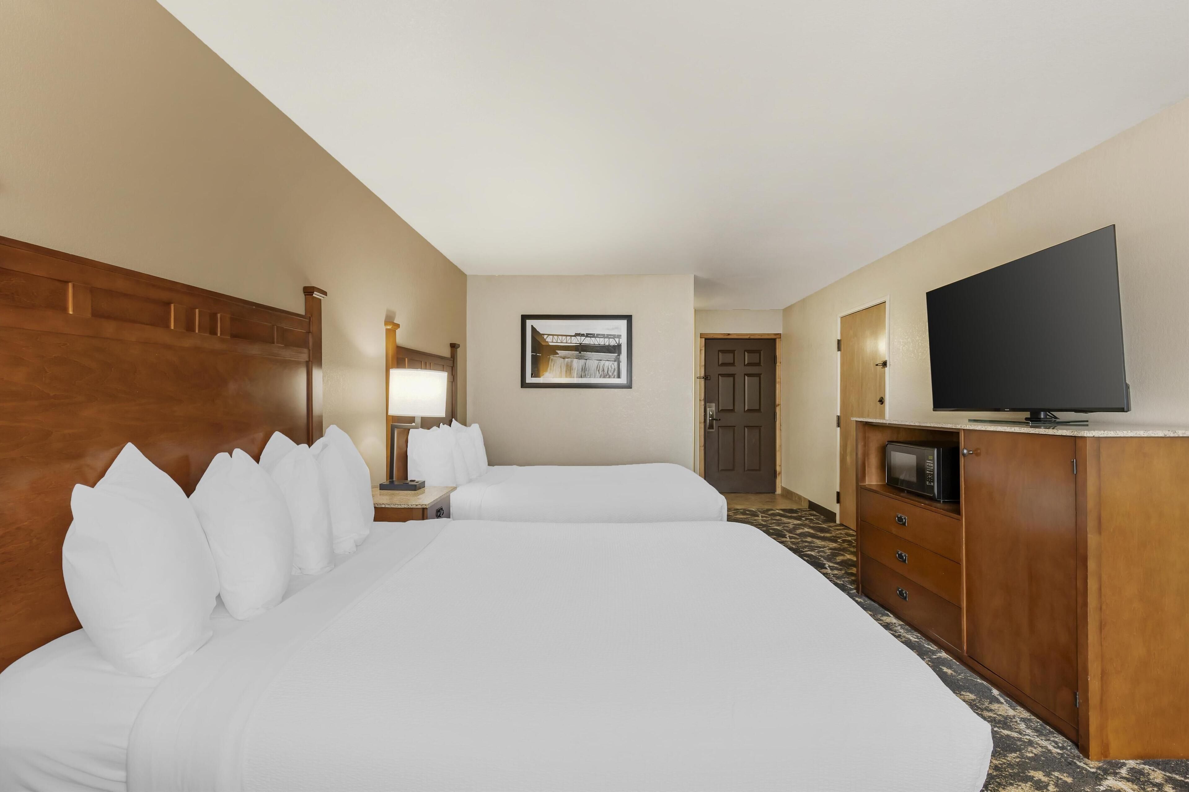 Une chambre d’hôtel avec deux lits, une télévision, un bureau et un four à micro-ondes.