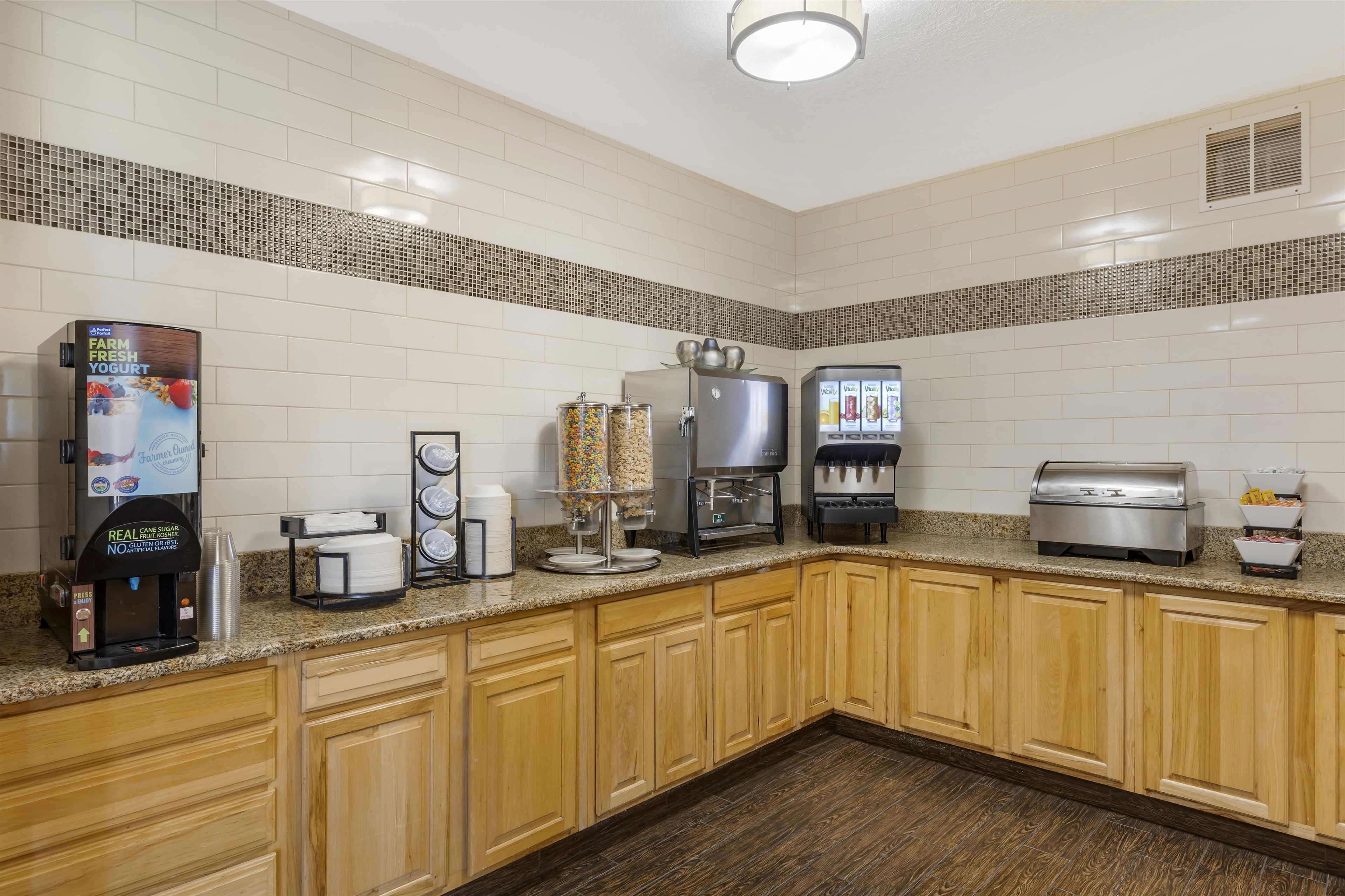 A commercial kitchen with a coffee machine, a yogurt dispenser, a beverage dispenser, and a buffet station.