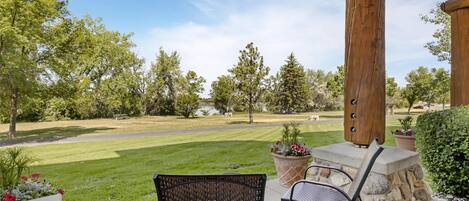 A patio area with outdoor furniture, a stone wall, and a view of a well-maintained lawn and trees.