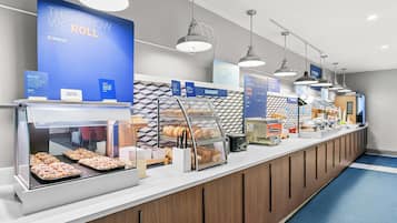 Zona de bufé con diferentes estaciones de comida, incluyendo una panadería y una sección de desayuno.