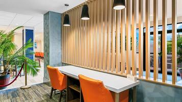 A modern interior with a long white table, two orange chairs, and a wooden slat partition.