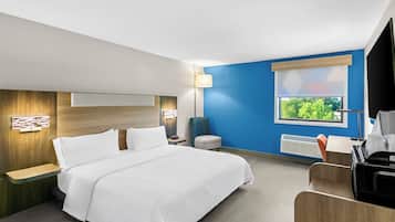 Una habitación de hotel con cama, mesitas de noche, escritorio, silla, lámpara, ventana con vistas y televisión.