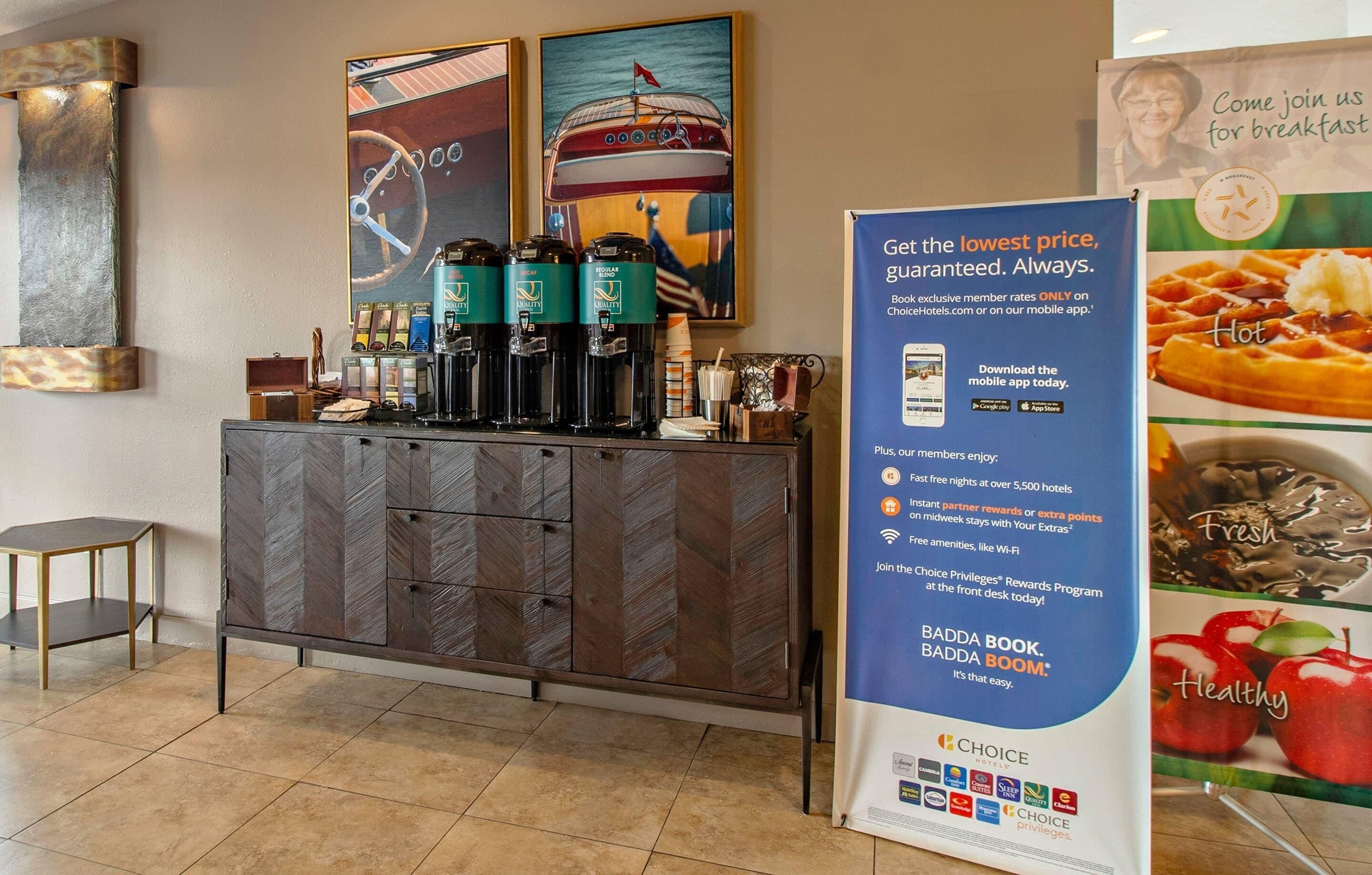 A reception area with a coffee station, a large sign promoting a rewards program, and artwork on the wall.