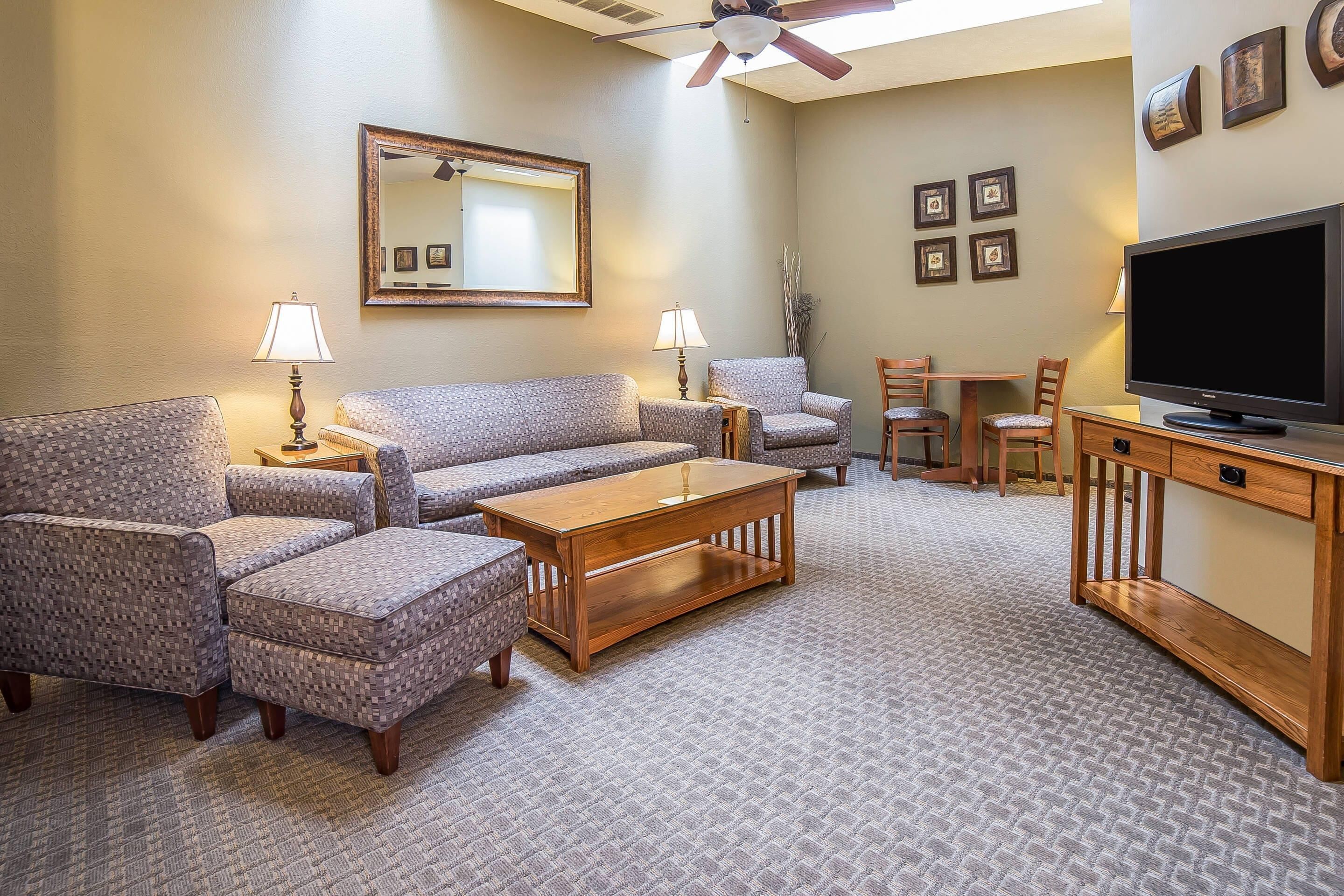 A living room with a sofa set, a coffee table, a TV, and a ceiling fan.