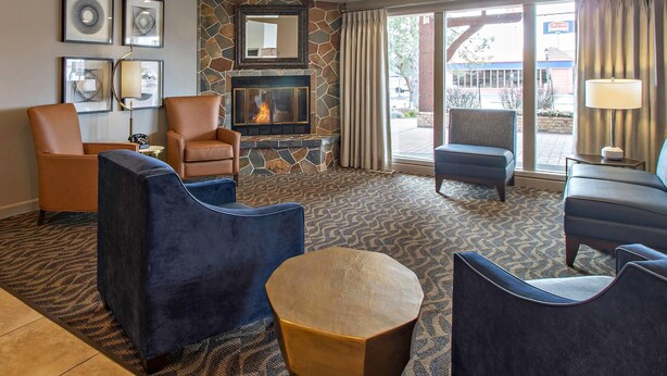 A hotel lobby with a stone fireplace, framed artwork, and comfortable seating. - Quality Inn & Suites Coeur d'Alene (Coeur d'Alene)