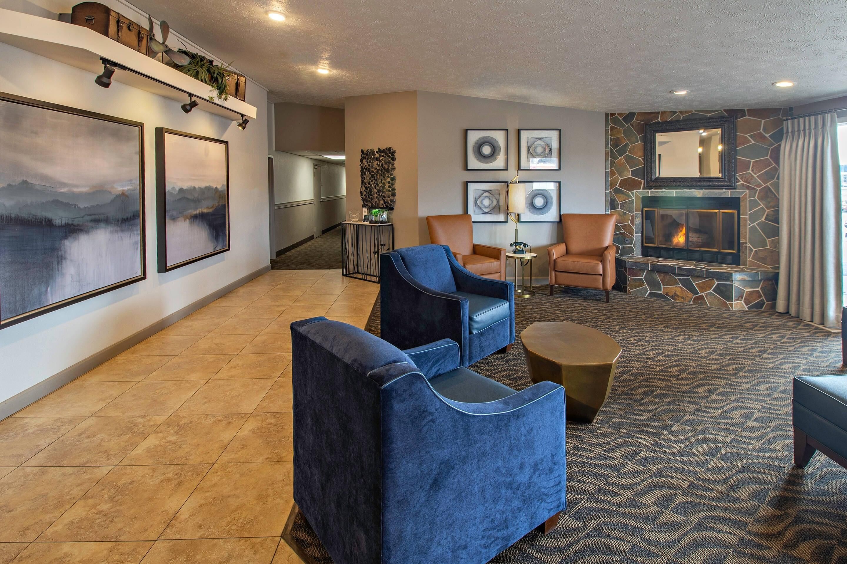 Un salon moderne avec une cheminée, des sièges confortables et des œuvres d’art accrochées aux murs.
