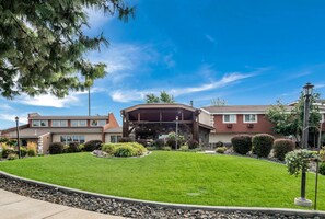 A modern building with a covered entrance, a well-maintained lawn, and a clear blue sky. - Quality Inn & Suites Coeur d'Alene (Coeur d'Alene)