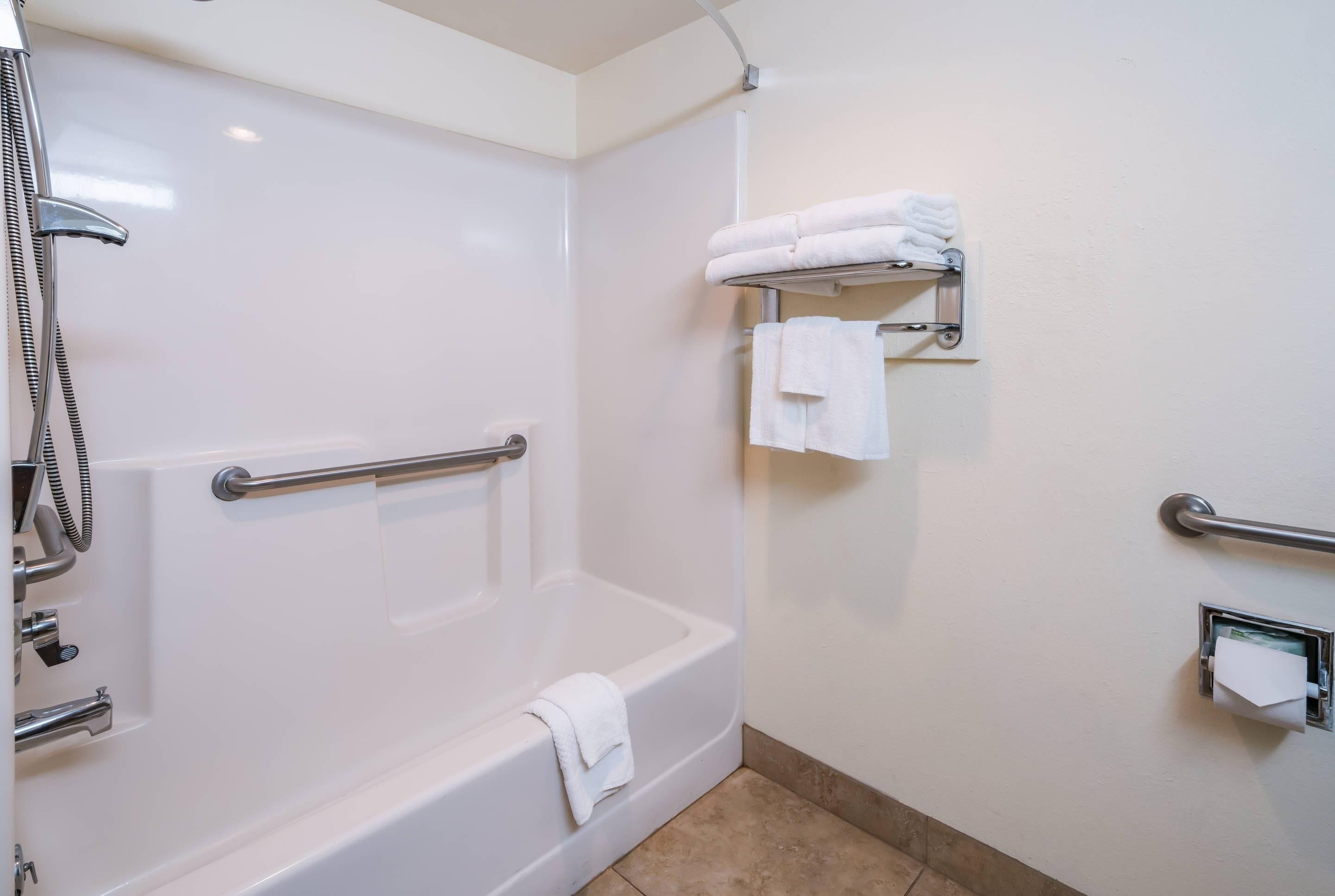 A bathroom with a walk-in shower, a bathtub, a towel rack, and a hand dryer.