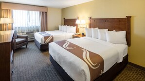 A hotel room with two beds, a desk, a chair, and a window with curtains. - Quality Inn & Suites Coeur d'Alene (Coeur d'Alene)