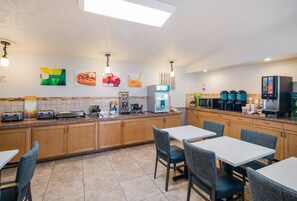 A modern kitchen with a breakfast bar, a coffee station, and a seating area with tables and chairs.