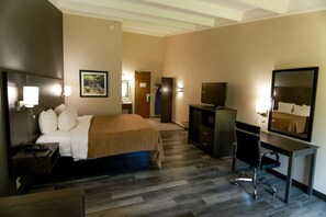 A hotel room with a bed, desk, TV, and a mirror. - Quality Inn & Suites Danbury near University (Danbury)