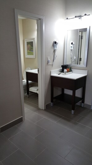 A bathroom with a white sink, a mirror, and a hairdryer mounted on the wall. - Quality Inn & Suites Danbury near University (Danbury)