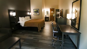 A hotel room with a bed, bedside table, desk, chair, and a mirror. - Danbury Inn & Suites (Danbury)
