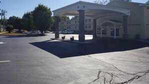 A hotel with a covered parking area, multiple columns, and a building with a flat roof.