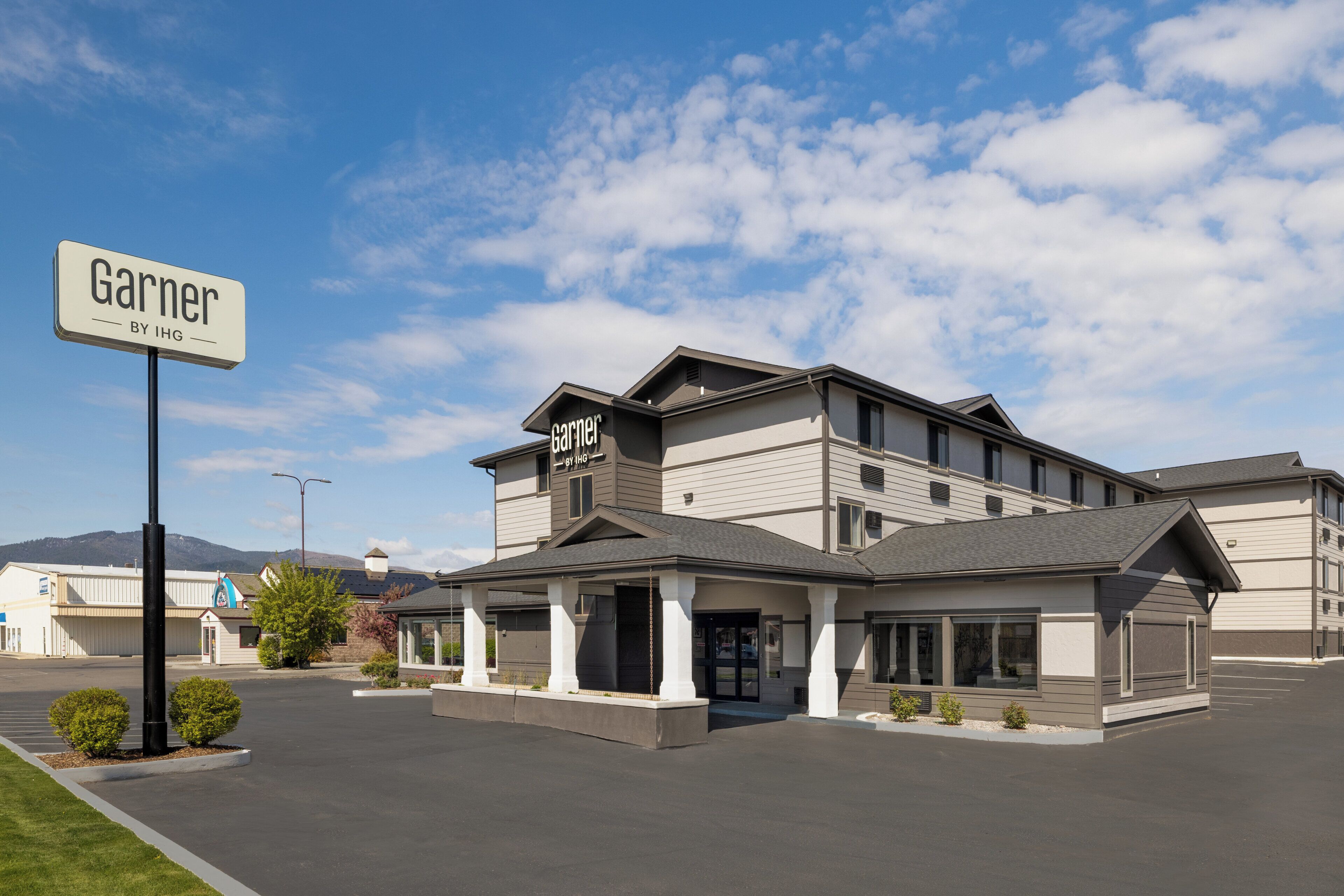 Un hôtel avec une enseigne bien visible indiquant « Garner BY IHG » et une entrée abritée.