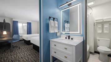 Ein Hotelzimmer mit Bett, Schreibtisch, Badezimmer mit Waschbecken und Spiegel sowie Toilette.