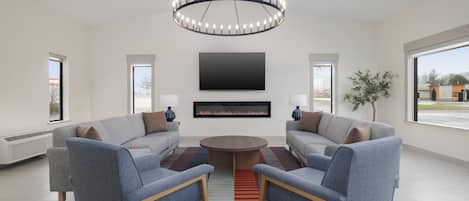 A modern living room with a central fireplace, two sofas, a coffee table, and a chandelier.