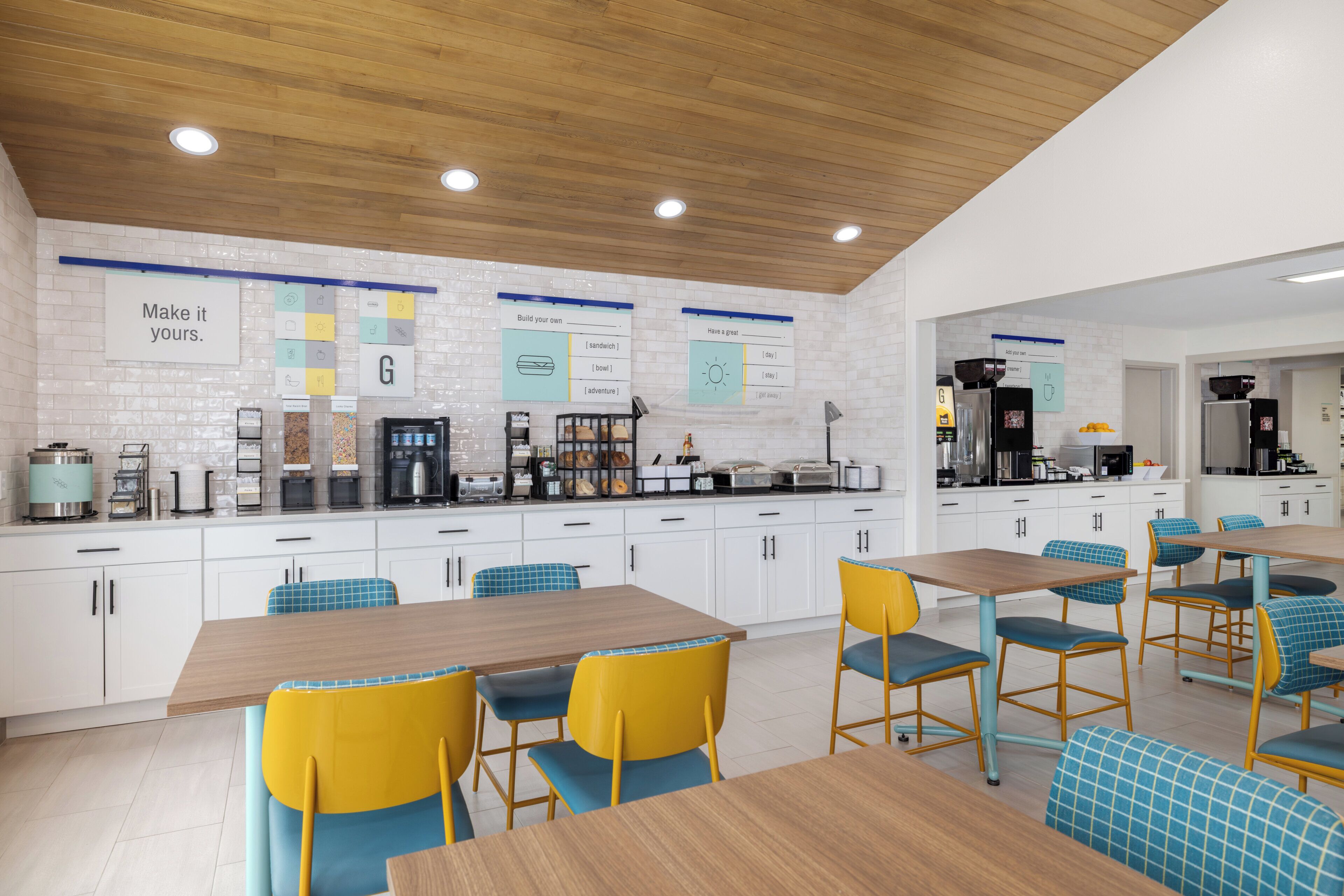 A modern kitchen with white cabinets, wooden countertops, and a variety of appliances. There are multiple seating areas with tables and chairs.