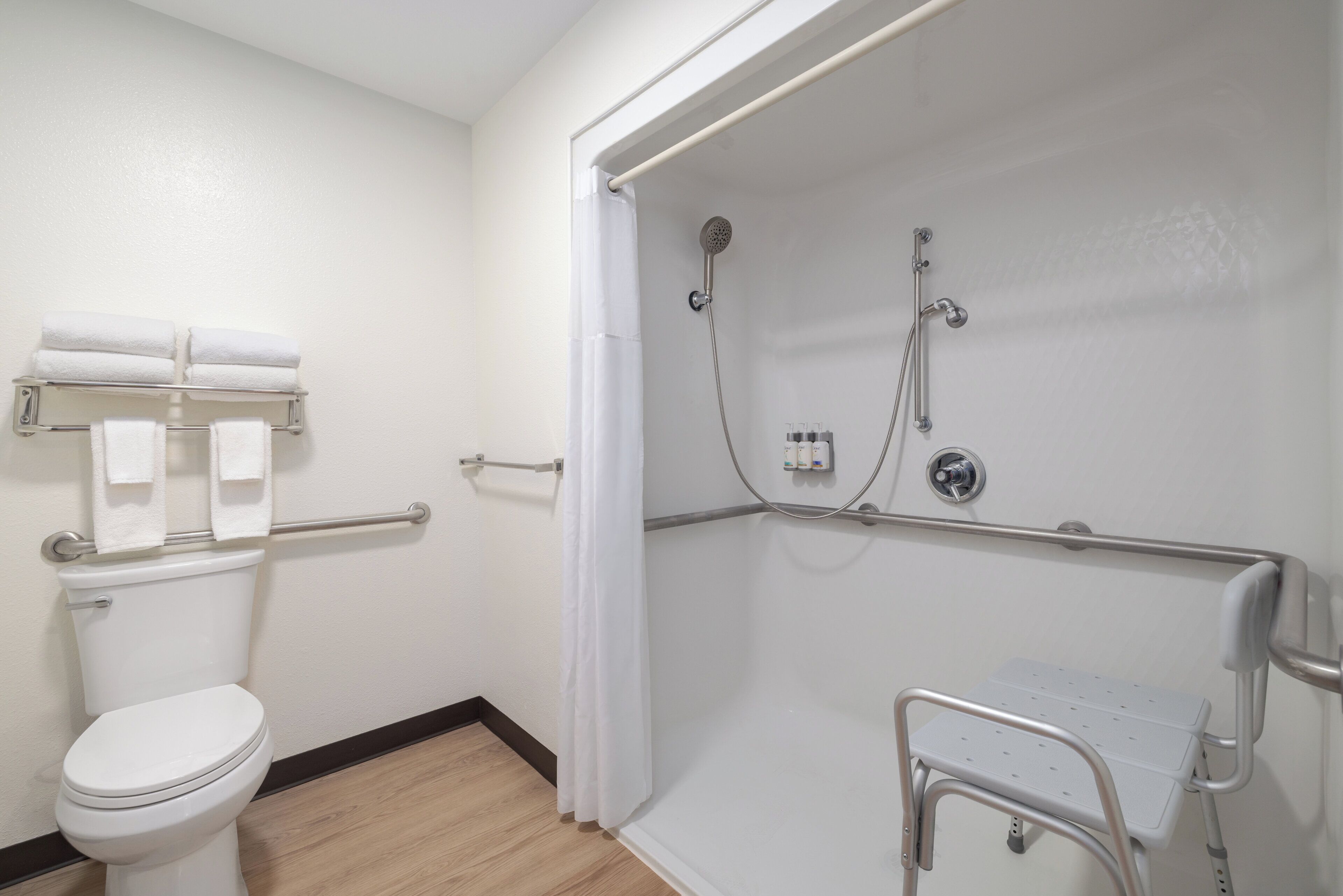 Een badkamer met toilet, douche met een handgreep en een handdoekrek.
