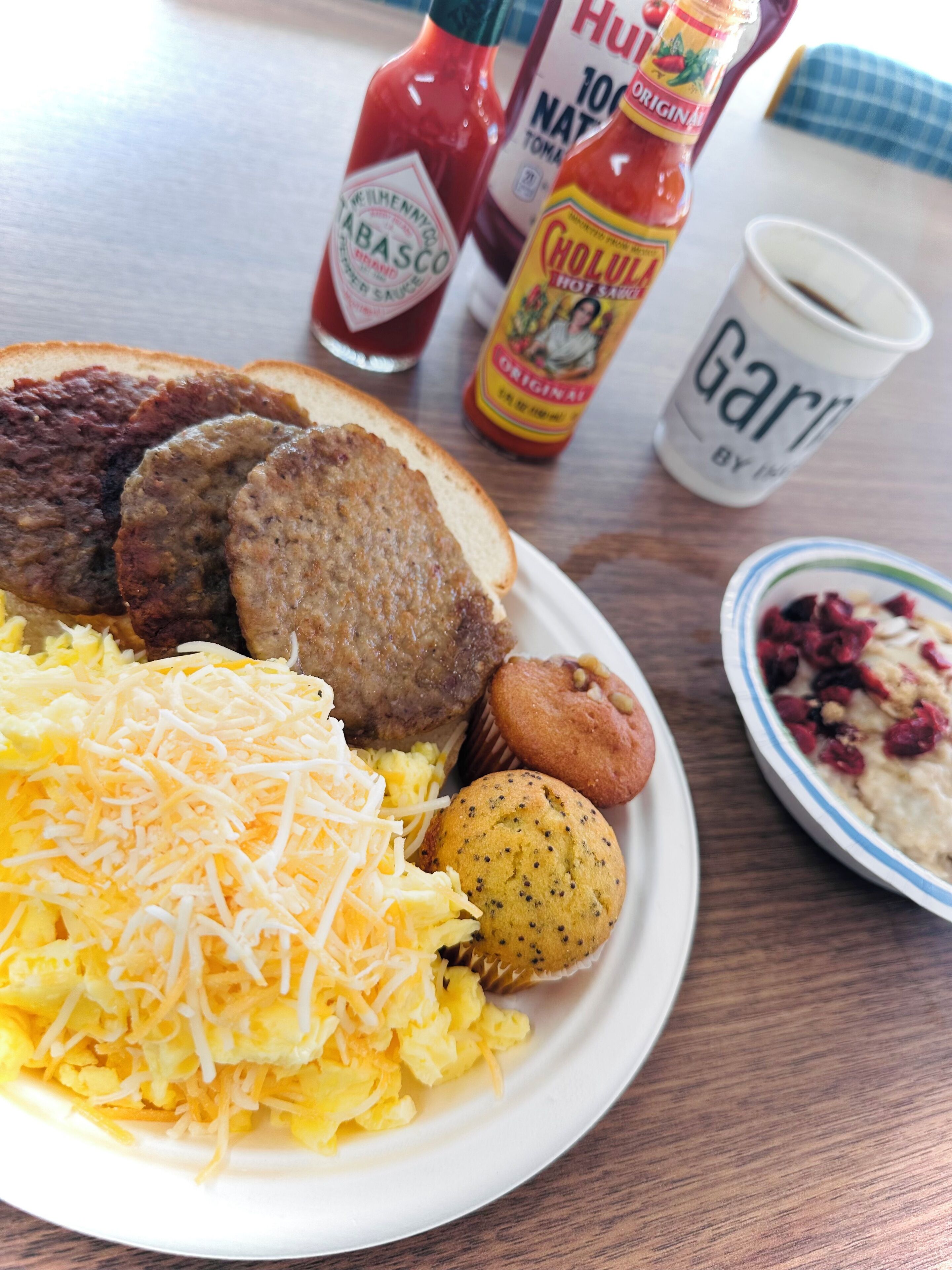 A breakfast plate with scrambled eggs, sausage, and a muffin.
