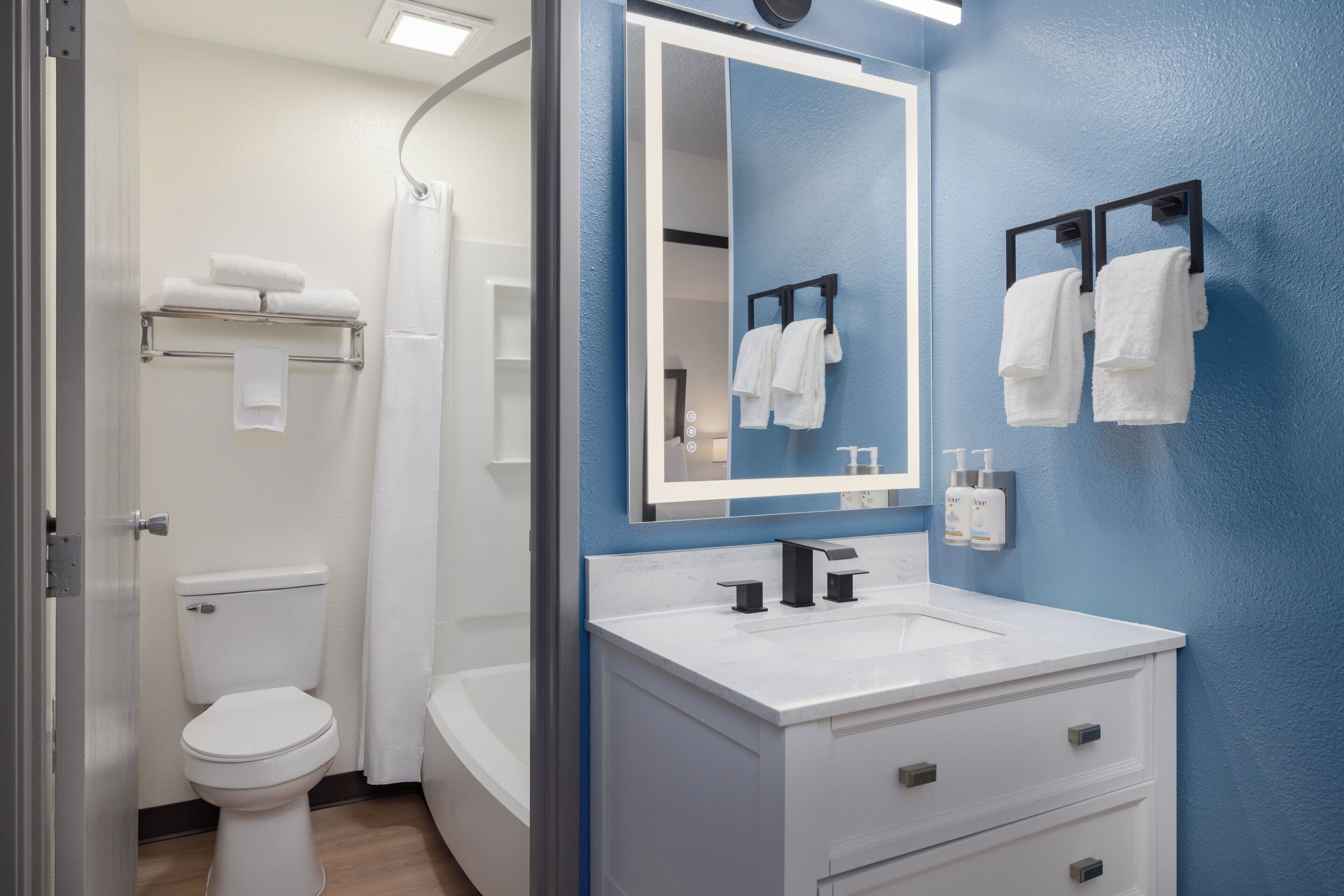 A bathroom with a white toilet, a white sink, a mirror, and towels on a rack.
