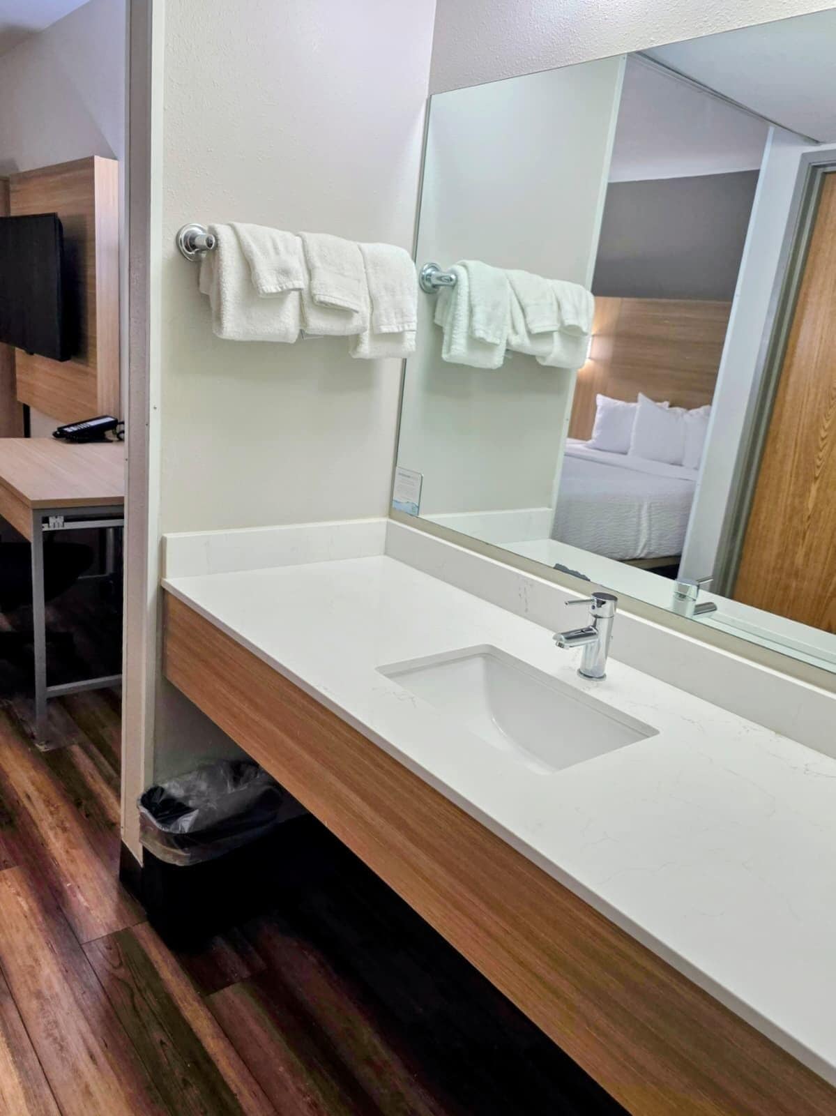 Un bany modern amb un lavabo blanc, un mirall i dues tovelloles penjades a ganxos.