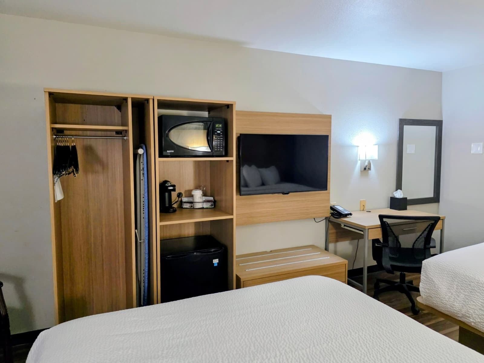 Hotelkamer met een kledingkast, een magnetron, een zithoekje, een bureau met stoel, en een bed.