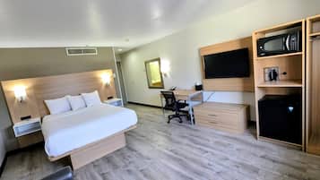 Een hotelkamer met een bed, bureau, stoel, kledingkast en televisie.