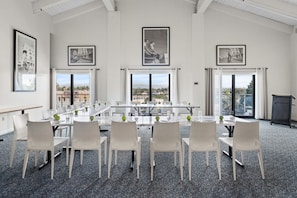A conference room with a long table, white chairs, and large windows with city views. - Hotel Erwin Venice Beach (Venice)