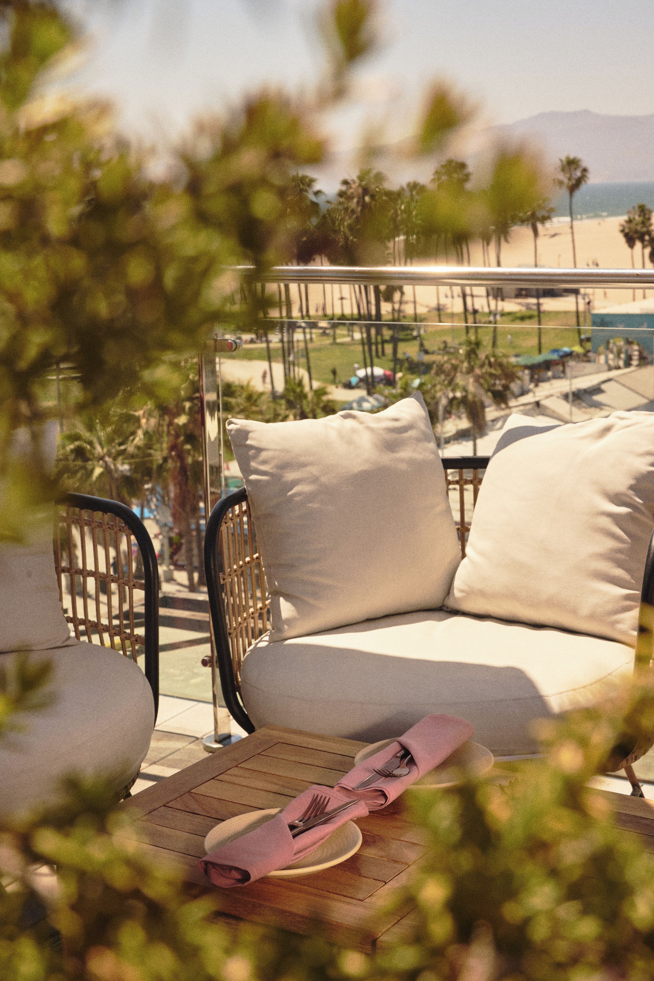 A balcony with a seating area, including a chair and a sofa, with a table in the foreground.