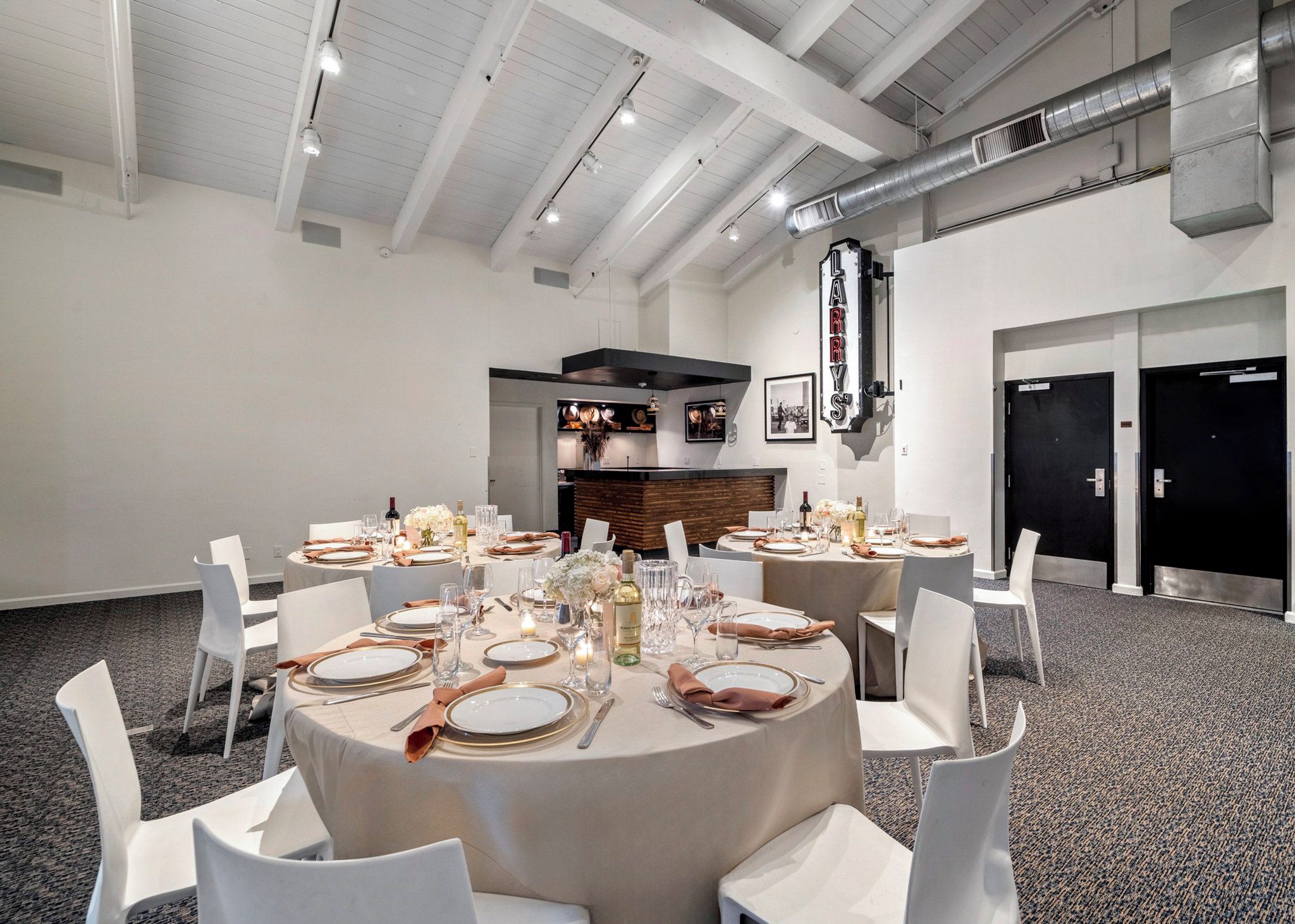 A conference room with round tables set for a formal event, featuring white chairs, table settings, and a central stage area.