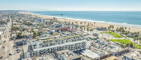 An aerial view of a coastal city with a beach, buildings, and a pier.