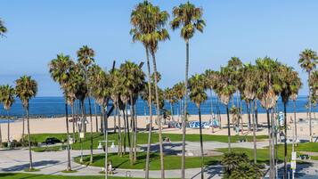 A beach with palm trees, a clear sky, and a view of the ocean.
