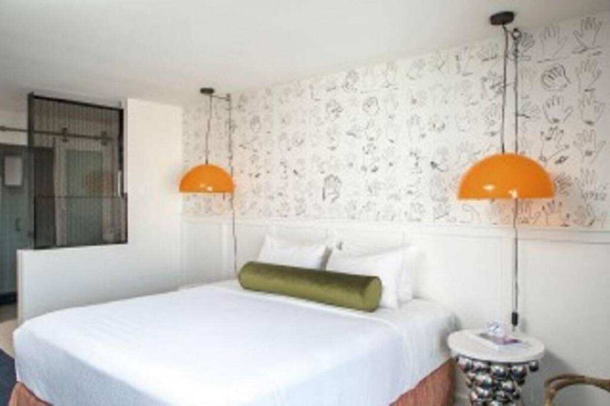A hotel room with a bed, two bedside lamps, a round table, and a patterned wall.
