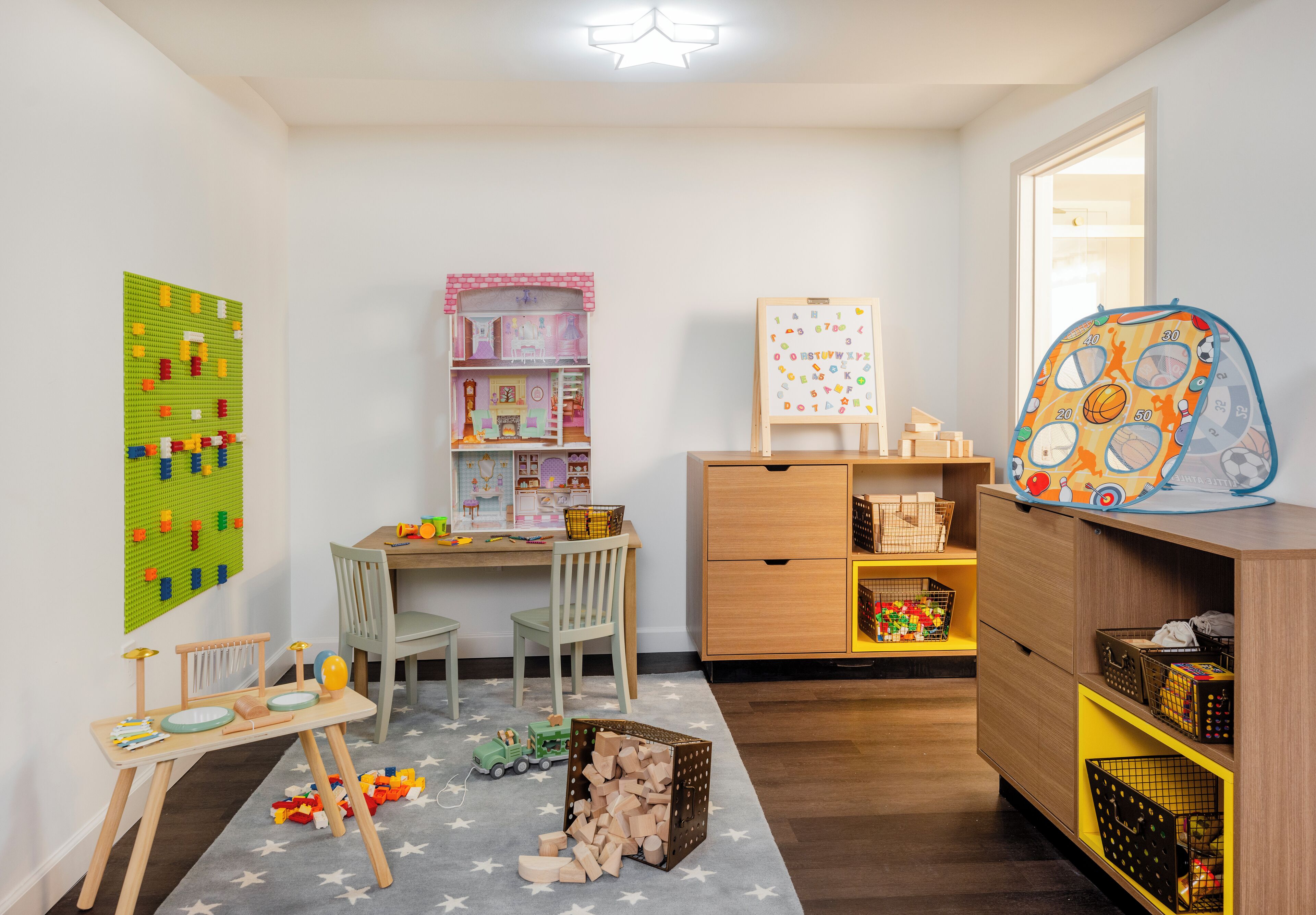 Un cuarto de juegos infantil con un tablero de pegboard, una cocina de juguete, un coche de juguete y una estantería.