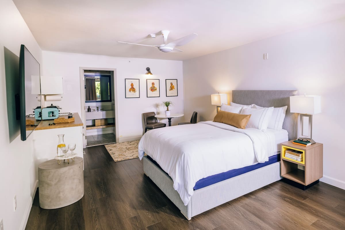 A modern hotel room with a large bed, bedside tables, a desk, and a ceiling fan.